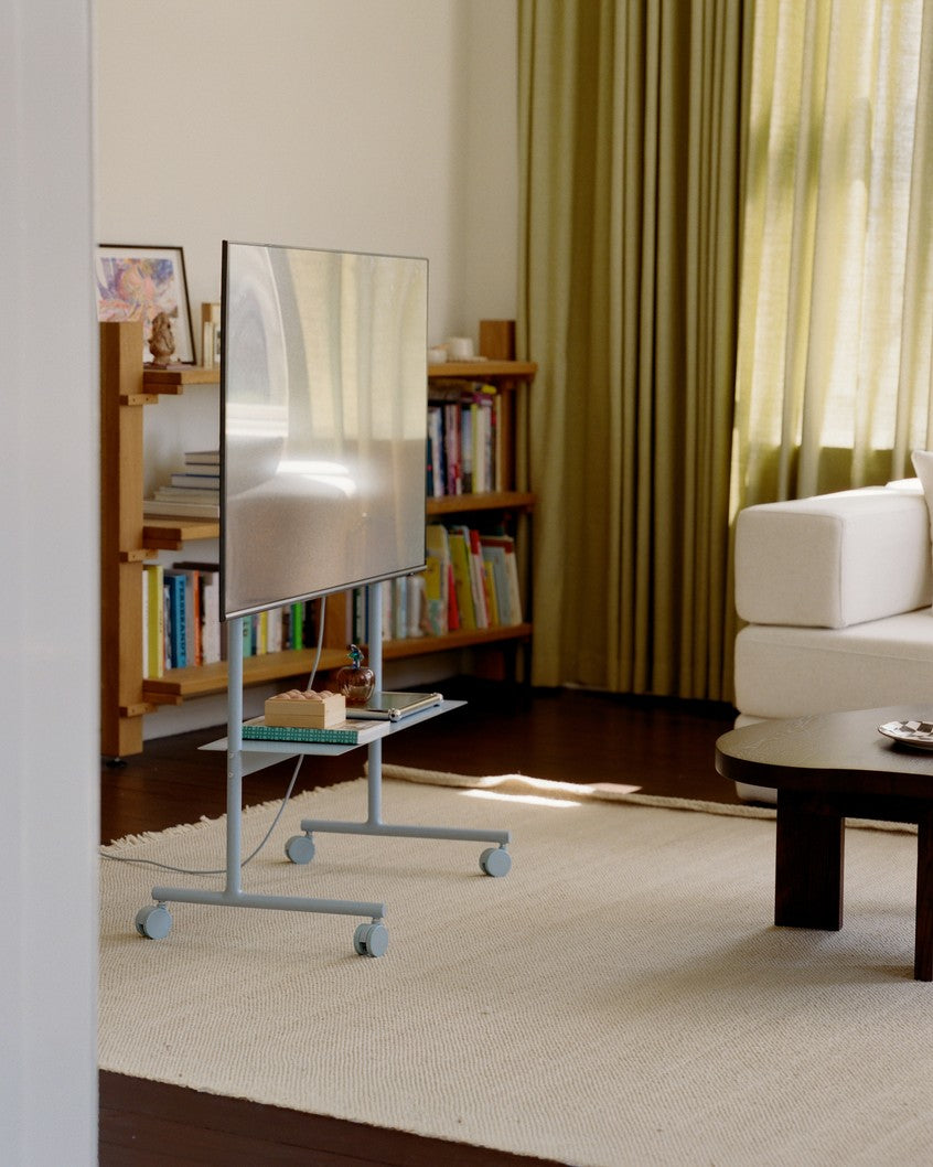 Rover in Powder Blue met tv in woonkamer, zijaanzicht met wielen, boekenkast en groene gordijnen op achtergrond