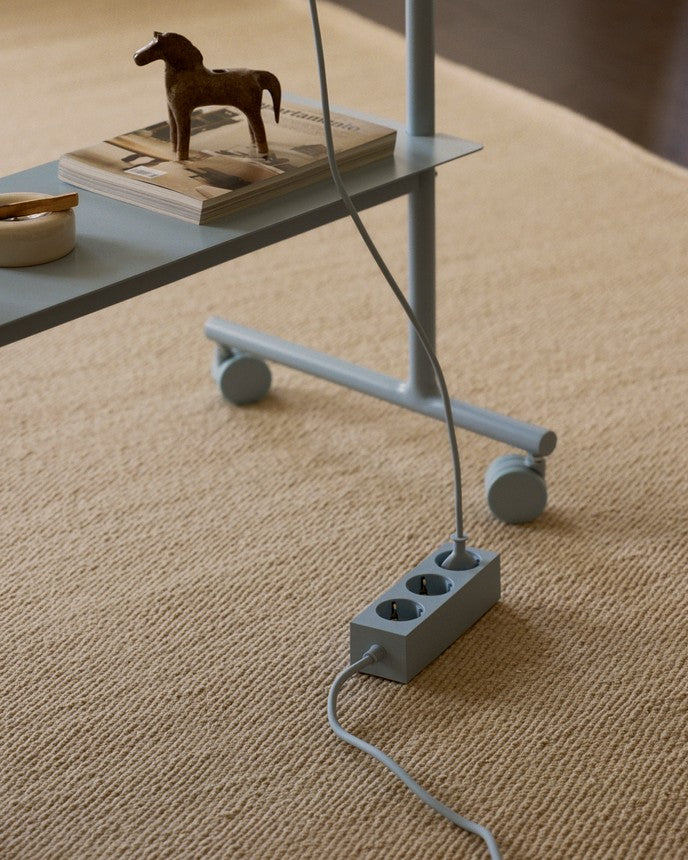 Rover in Powder Blue op wollen vloerkleed, detail van wielen en onderstel, met stekkerdoos en boeken op de plank